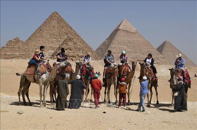Du khách cưỡi lạc đà tham quan kim tự tháp ở ngoại ô thủ đô Cairo, Ai Cập. Ảnh: AFP/TTXVN