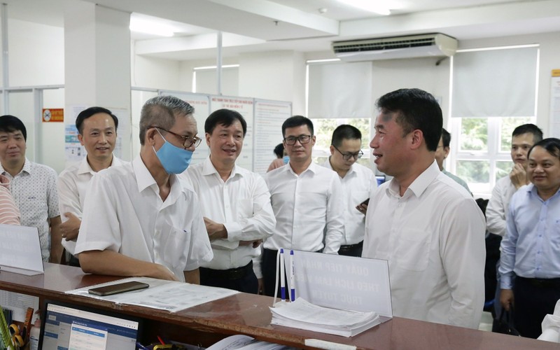 Lãnh đạo Bảo hiểm xã hội Việt Nam trao đổi với người dân đến làm thủ tục tại Bộ phận một cửa của Bảo hiểm xã hội Thành phố Hồ Chí Minh. (Ảnh TÂM TRUNG)