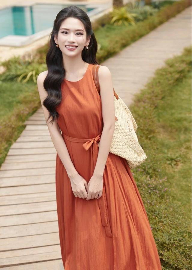 Gam màu cam tươi tắn, rạng rỡ nhưng vẫn mang nét trưởng thành thanh lịch cho nàng. Váy suông có thể làm điệu thêm bằng cách buộc hờ dây vải quanh eo, phối cùng túi thủ công đan từ nan tre, cói, lục bình...