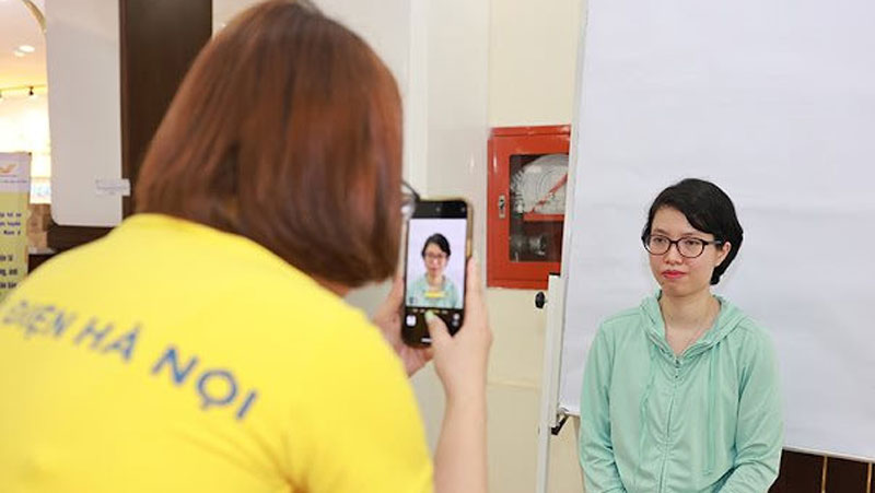Nhân viên Bưu điện Hà Nội hỗ trợ người dân đến thực hiện các dịch vụ công trực tuyến trên Cổng Dịch vụ công quốc gia. Ảnh: Quốc Bảo