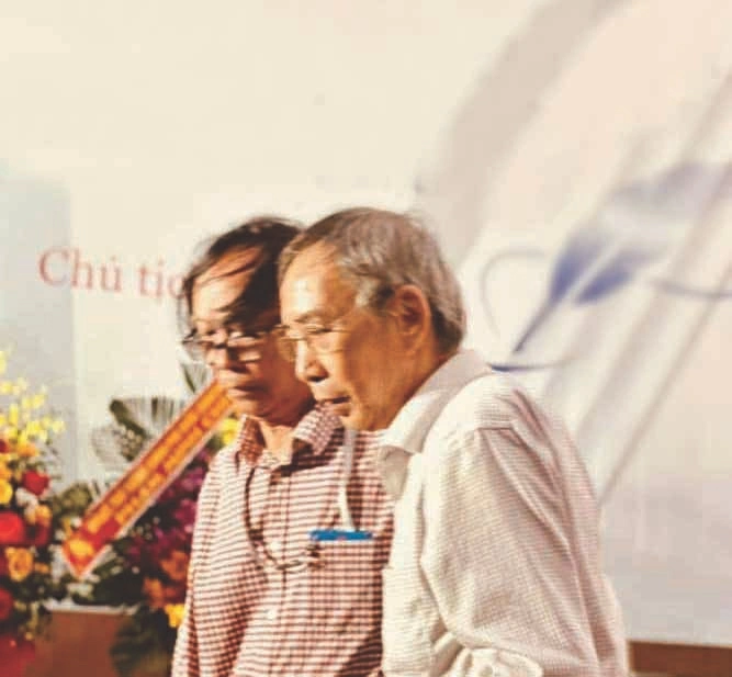 Nhà thơNguyễn Việt Chiến dìu nhà thơ Thanh Thảo (bên phải) lên đọc thơ trong Đêm thơ Mùa thu ở Hải Phòng.
