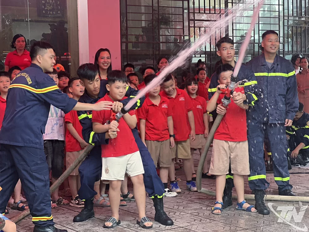 Học sinh Trường Mầm non và Tiểu học DPA thực hành sử dụng vòi nước chữa cháy dưới sự hướng dẫn của cán bộ Phòng Cảnh sát PCCC và CNCH, Công an tỉnh Thái Nguyên.