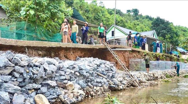 Lực lượng chức năng xã Tân Hợp đan rọ sắt gia cố kè đường giao thông nông thôn nhằm bảo đảm an toàn cho người dân.