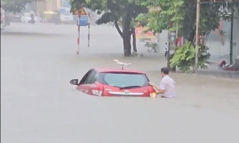 Một chiếc ô tô bị ngập sâu khi di chuyển trên đường tại khu vực phường Thịnh Đán.