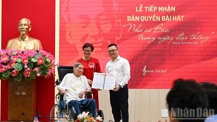 Tổng Biên tập Lê Quốc Minh nhận bản thảo bài hát Như có Bác trong ngày đại thắng có chữ ký đề tặng của nhạc sĩ Phạm Tuyên. (Ảnh: THÀNH ĐẠT)