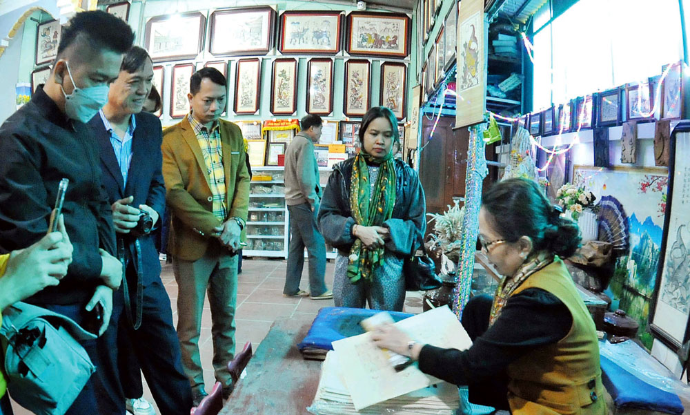 Nghệ nhân Nguyễn Thị Oanh giới thiệu với du khách công đoạn sản xuất tranh.