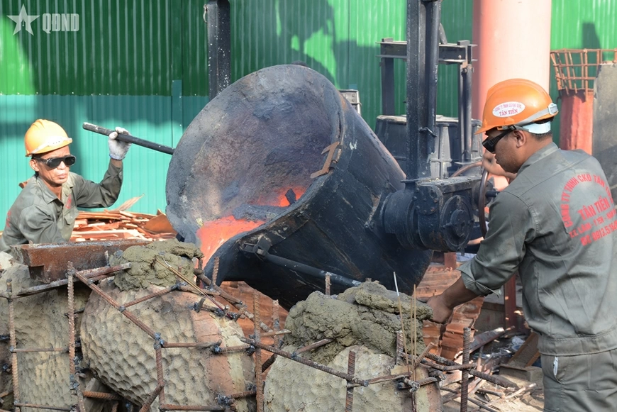 Các nghệ nhân và công nhân rót đồng nung chảy vào khuôn đúc. 