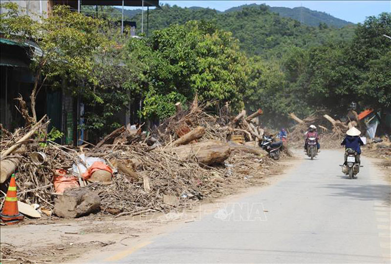 Vô số thân cây, khúc gỗ lớn và rác án ngữ trước dãy nhà dân làm ảnh hưởng đến đời sống, sinh hoạt, đi lại của nhiều gia đình. Ảnh: Xuân Tiến/TTXVN