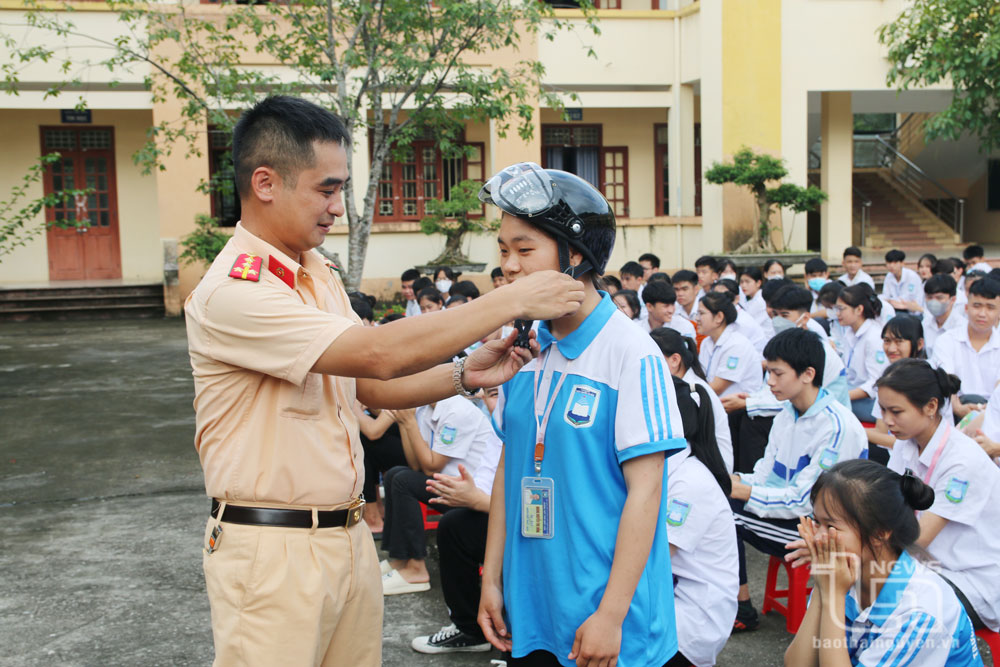 Cảnh sát giao thông Đồng Hỷ tặng mũ bảo hiểm và hướng dẫn học sinh Trường THPT Trần Quốc Tuấn cài mũ bảo hiểm đúng quy cách.