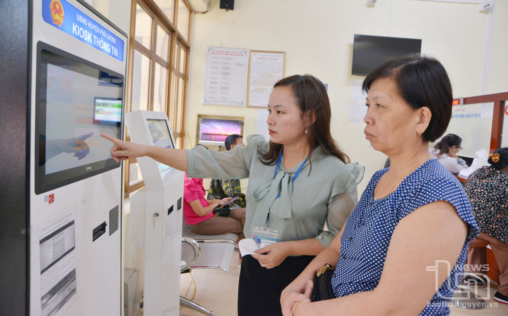 Cán bộ tại Bộ phận một cửa của huyện Phú Lương hướng dẫn người dân lấy số tự động và tra cứu thông tin về thủ tục hành chính.