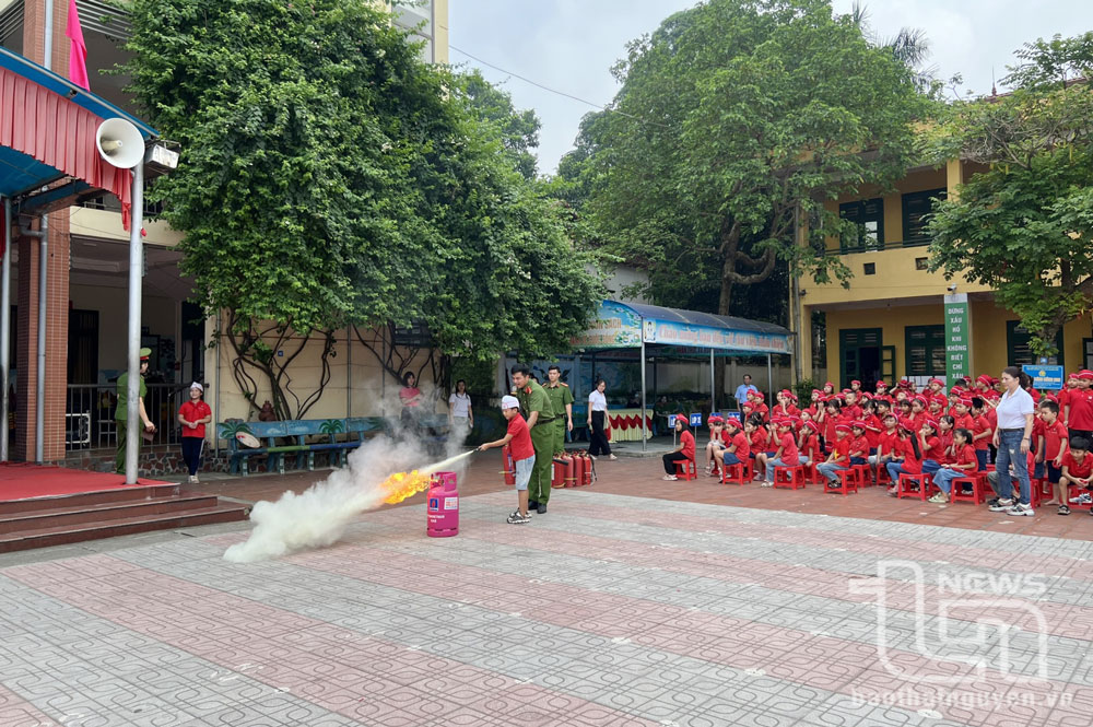 Cán bộ, chiến sĩ công an hướng dẫn học sinh Trường Tiểu học Nguyễn Huệ (TP. Thái Nguyên) thực hành, trải nghiệm dập tắt đám cháy bằng phương tiện chữa cháy.