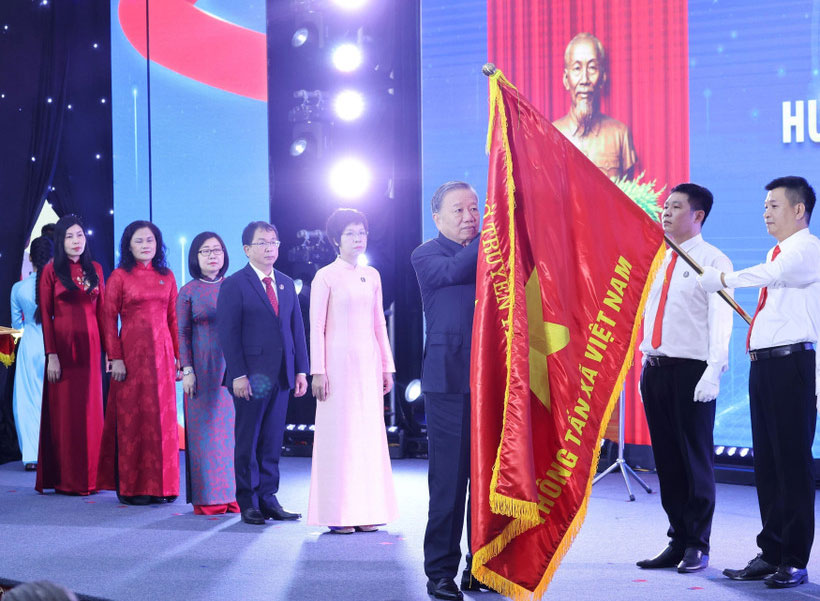 Tổng Bí thư Tô Lâm gắn Huân chương Hồ Chí Minh lên lá cờ truyền thống Thông tấn xã Việt Nam.