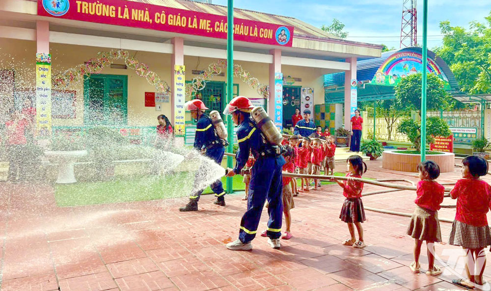 Các bé mầm non làm quen với vòi phun nước chữa cháy.