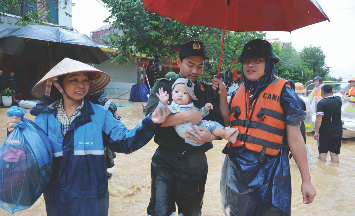 Lực lượng chức năng hỗ trợ đưa người dân ra khỏi khu vực ngập lụt đến nơi an toàn.