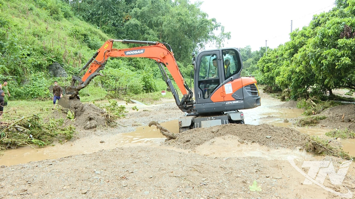 Máy xúc đang san gạt một tuyến đường vào thôn Nà Nguộc, xã Tân Kỳ.
