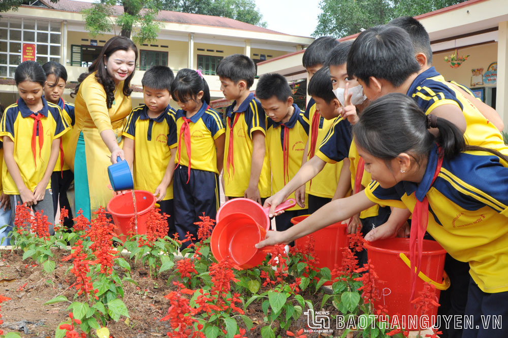 Cô giáo Vũ Thị Thanh, Hiệu trưởng Trường Tiểu học Hương Sơn (Phú Bình), cùng học sinh chăm sóc cây, hoa trong khuôn viên Trường.