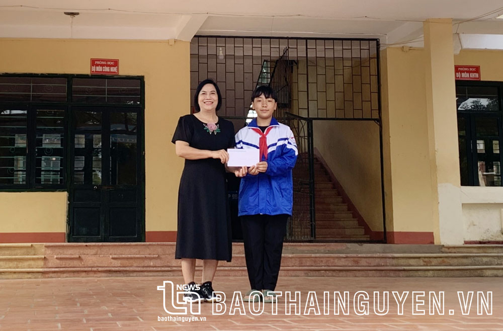 Cô giáo Ngô Thị Hường, Hiệu trưởng Trường THCS thị trấn Hương Sơn (Phú Bình) khen thưởng em Nguyễn Quang Minh, học sinh lớp 9D.