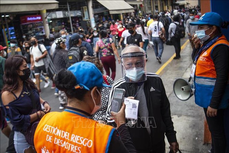 Nhân viên an ninh kiểm tra chứng nhận tiêm vaccine phòng COVID-19 của người dân tại một khu chợ ở Lima, Peru, ngày 10/12/2021. (Ảnh: AFP/TTXVN)
