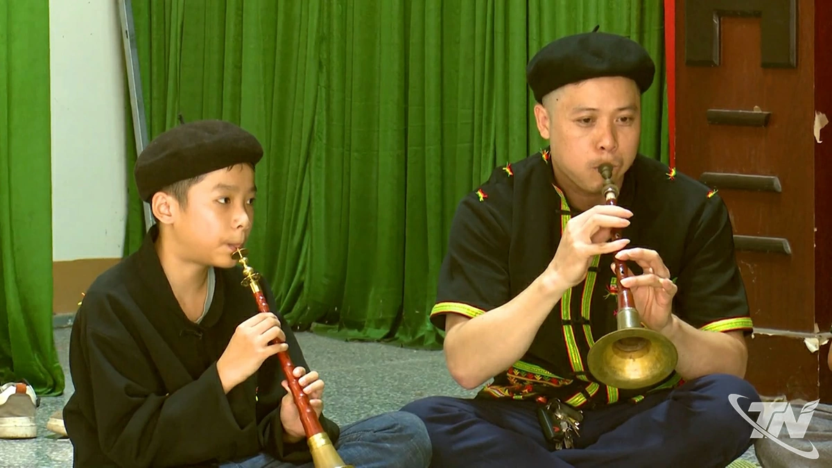  Em Triệu Tấn Phát (bên trái), người Dao  
thôn Mỏ Sắt luyện tập thổi kèn Pí Lè  
cùng người lớn trong bản.
