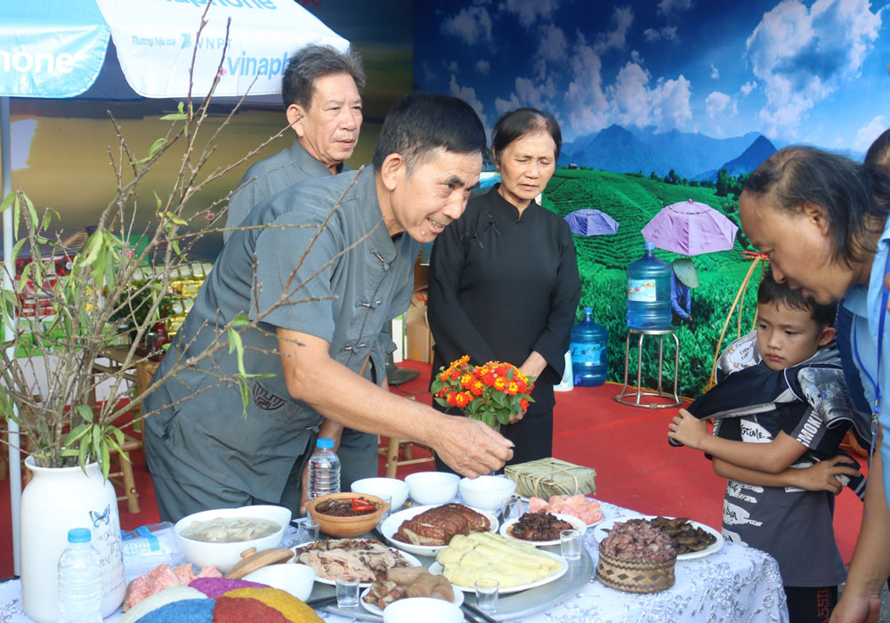 Nghệ nhân Thẩm A Chiến (bên trái) giới thiệu với du khách về mâm cơm của dân tộc Ngái vào ngày Tết Nguyên đán, trong đó có món Khau nhục truyền thống.