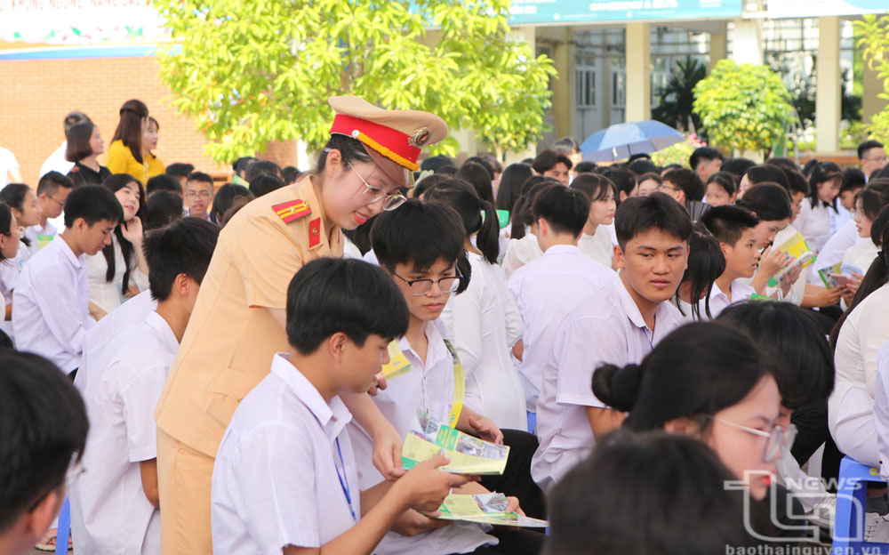 Cảnh sát giao thông (Công an tỉnh) phát tờ rơi tuyên truyền, phổ biến pháp luật về ATGT cho học sinh THPT.